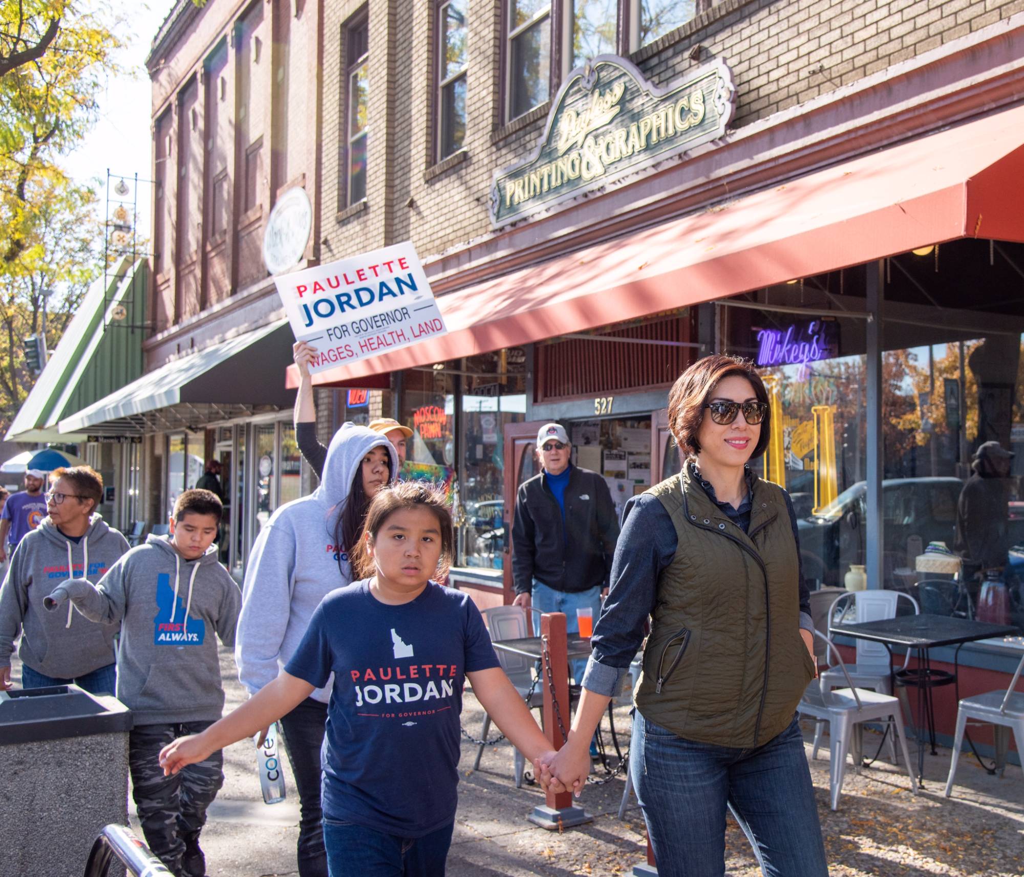 Paulette Jordan walking a parade route hand in hand with a child